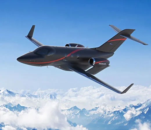 Private jet flies in blue sky above the clouds